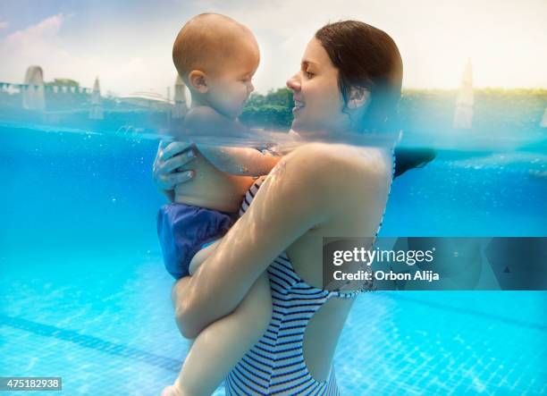 mutter mit baby junge im pool - babyschwimmen stock-fotos und bilder