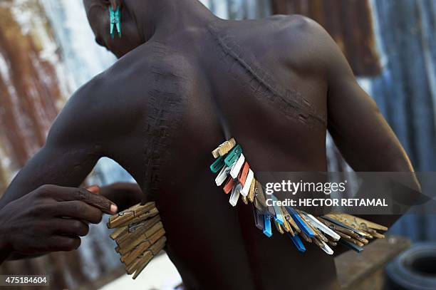 Man helps his friend to remove clothespins from his back while they play dominoes in the neighbourhood of Nere, in Cite Soleil, in Port-au-Prince, on...