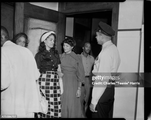 Wanda Jackson, Mrs John Hicks, Elmer Taylor, and police officer John Hicks, standing in hallway, Pittsburgh, Pennsylvania, June 15, 1949.