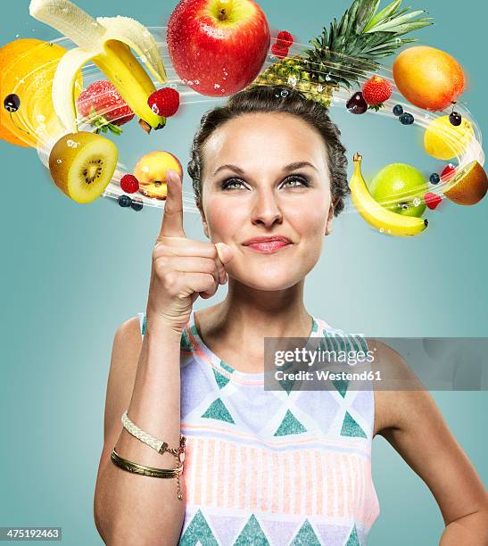 young woman with flying fruits around her head, composite - food flying stock-fotos und bilder