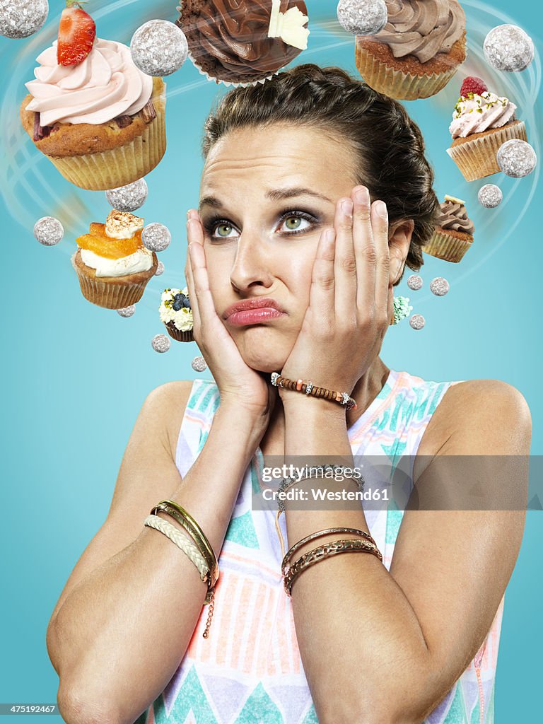 Young woman with flying cupcakes around her head, Composite