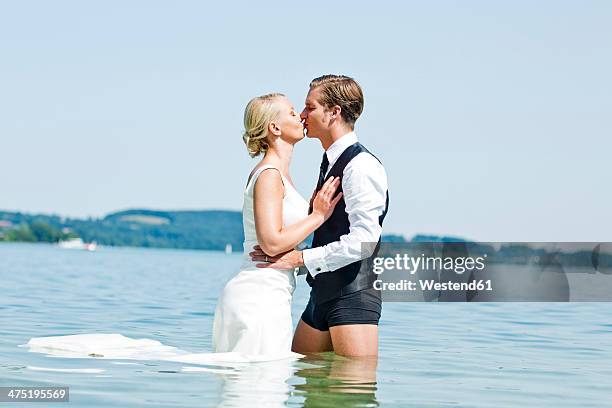 germany, bavaria, tegernsee, wedding couple standing in lake, kissing - swimming shorts stock pictures, royalty-free photos & images