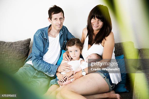 young family with male newborn and little daughter sitting on sofa at home - lying on back girl on the sofa stock pictures, royalty-free photos & images