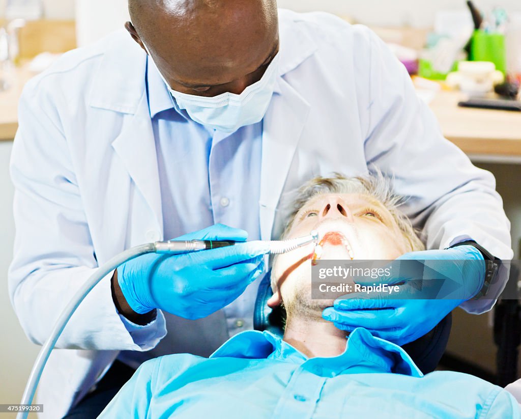 Dentist drills a male patient's teeth