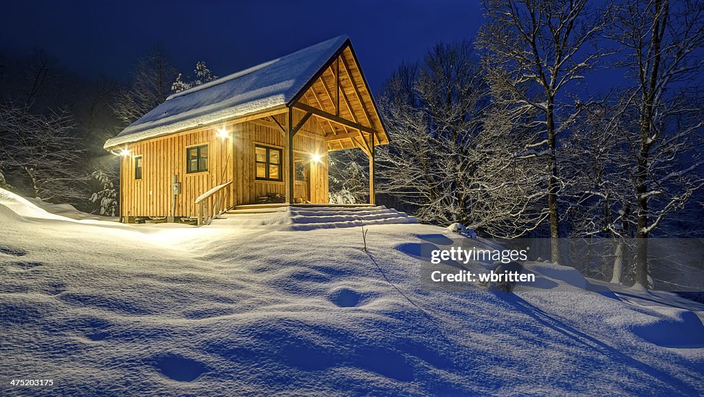 Rustic cabin in winter blizzard snowstorm at night