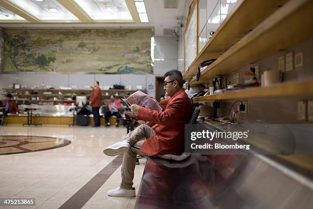 Trader reads a newspaper as he sits on the side of the trading hall of the Chinese Gold and Silver Exchange Society in Hong Kong, China, on...