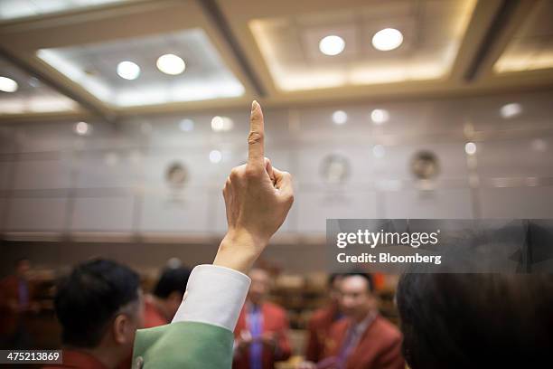 An employee of the Chinese Gold and Silver Exchange Society raises a finger in the company's trading hall in Hong Kong, China, on Wednesday, Feb. 26,...