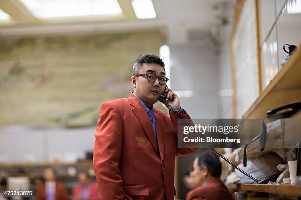 Trader uses a telephone in the trading hall of the Chinese Gold and Silver Exchange Society in Hong Kong, China, on Wednesday, Feb. 26, 2014. Gold...