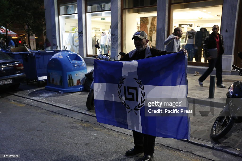 A Golden Dawn sympathizer carries an unofficial simple cross...