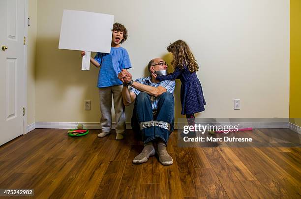 zwei kinder mit ihrem vater, als geisel mit isolierband - son in law stock-fotos und bilder
