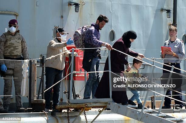 Belgian sailors help migrants off the Godetia logistical support ship of the Belgian Navy on May 30, 2015 upon its arrival in the port of Crotone in...