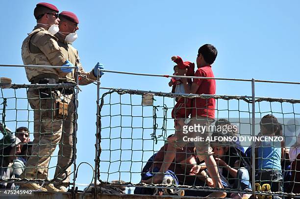 Belgian sailors help migrants aboard the Godetia logistical support ship of the Belgian Navy on May 30, 2015 upon its arrival in the port of Crotone...