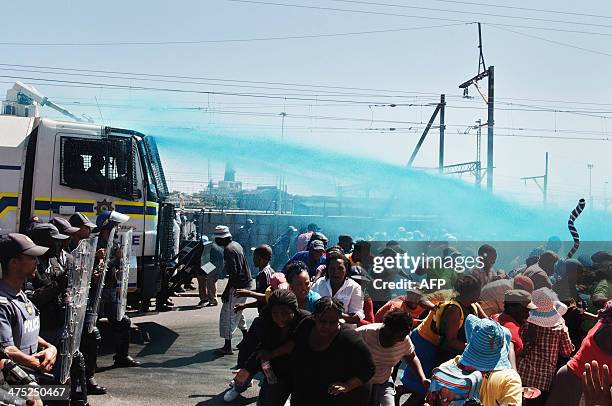 People taking part in a protest against poor sanitation run away from a water cannon and stun grenades fired by members of the South African Police...