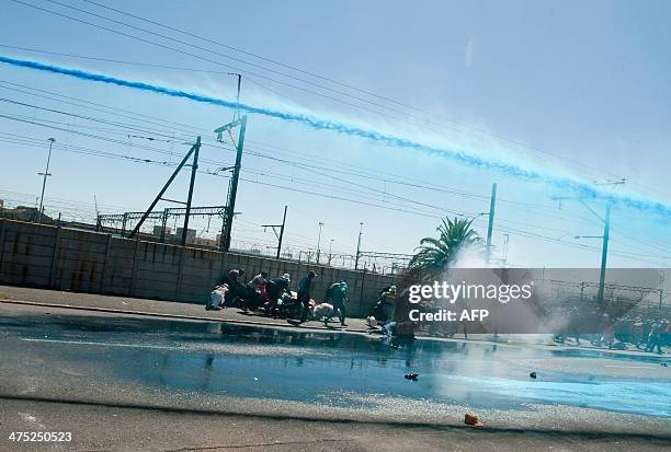 People taking part in a protest against poor sanitation run away from a water cannon and stun grenades fired by members of the South African Police...