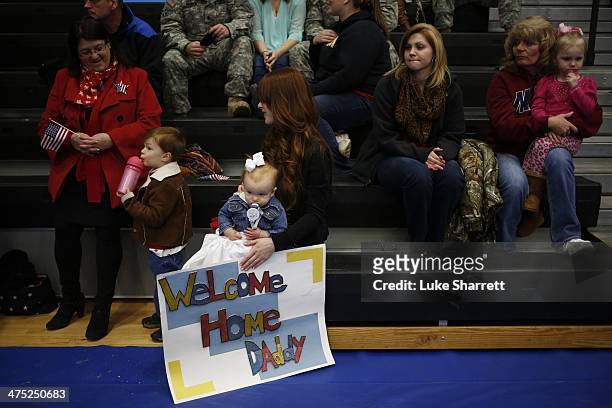 Army wife holds her daughter Annalise and a welcome home sign while waiting to greet her husband Spc. Eric Henry of the U.S. Army's 3rd Brigade...