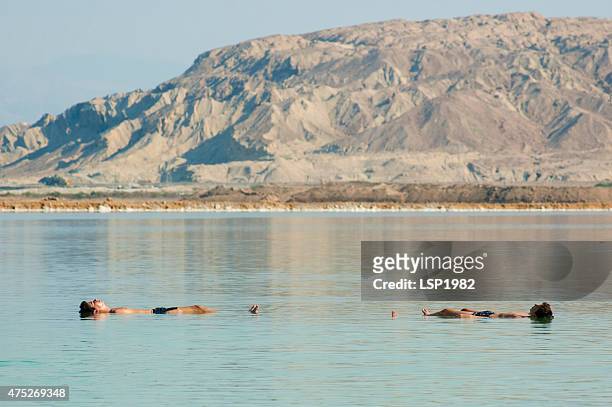two men floating in the dead sea - dead sea float stock pictures, royalty-free photos & images