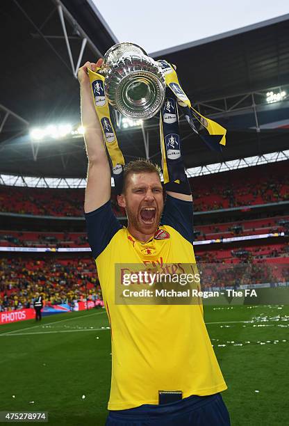 Per Mertesacker of Arsenal celebrates on the pitch with the trophy after winning the FA Cup Final between Aston Villa and Arsenal at Wembley Stadium...