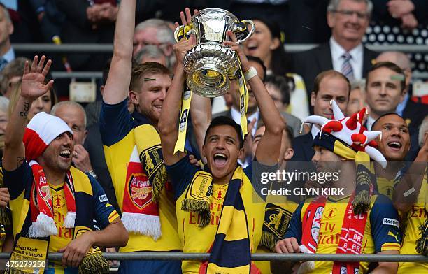 Arsenal's Chilean striker Alexis Sanchez holds up the trophy as Arsenal's Spanish midfielder Santi Cazorla , and Arsenal's English midfielder Jack...