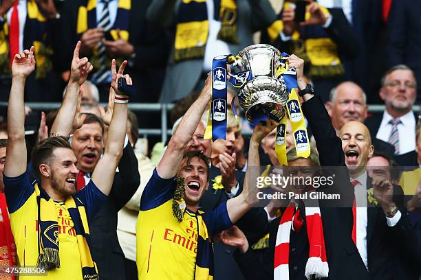 Nacho Monreal of Arsenal and Arsene Wenger manager of Arsenal lift the winners trophy following the FA Cup Final between Aston Villa and Arsenal at...