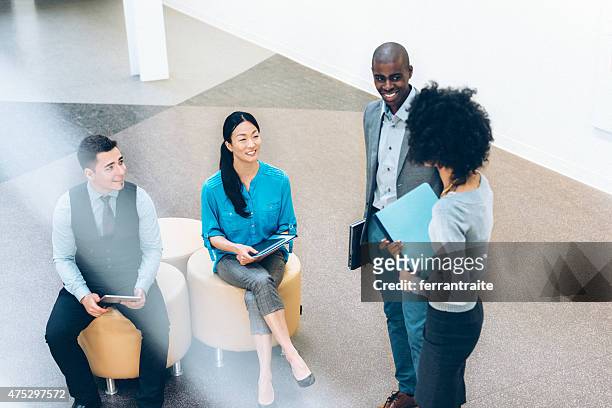 casual business meeting in the lobby - four people and meeting stock pictures, royalty-free photos & images