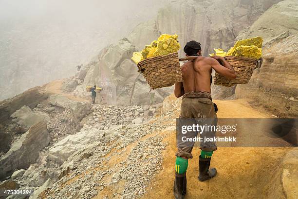asiatische arbeiter tragen körbe der schwefel in ijen-vulkan - sklaven stock-fotos und bilder