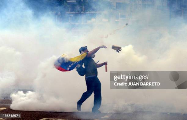 Demonstrator throws stones at riot policemen during an anti-government protest in eastern Caracas on February 27, 2014. Dueling demos of pro- and...