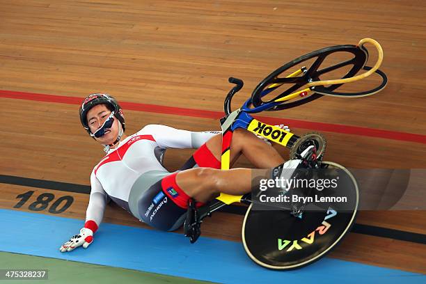 Yuta Wakimoto of Japan slides down the track after crashing during his heat of the Men's Keirin on day two of the 2014 UCI Track Cycling World...