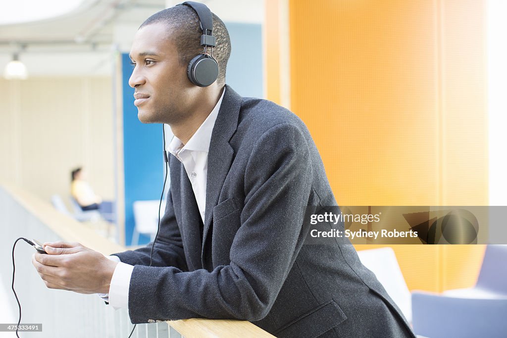 Businessman listening to headphones in office