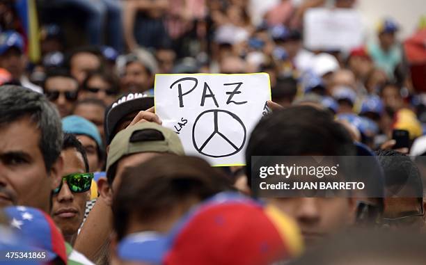 An anti-government demonstrator holds a paper reading "peace", during a protest in eastern Caracas on February 27, 2014. Dueling demos of pro- and...