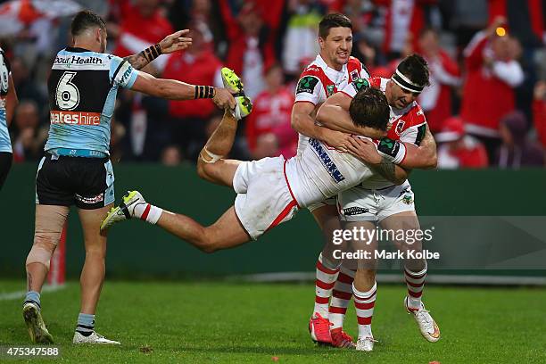 Jack Bird of the Sharks holds the leg of Mitch Rein of the Dragons as he celebrates with his team mates after scoring a try during the round 12 NRL...