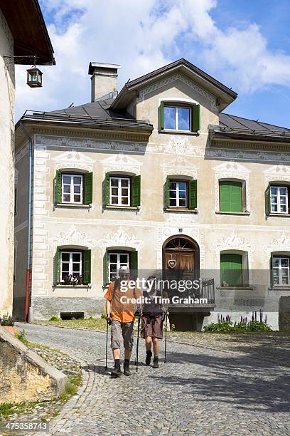 Tourists in the Engadine Valley village of Guarda with old painted stone 17th Century buildings, Switzerland