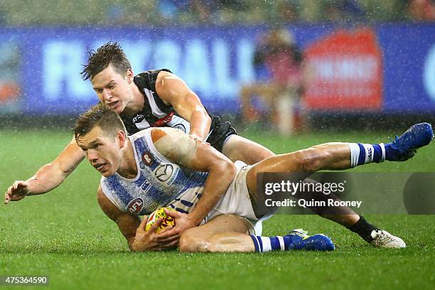 Shaun Higgins of the Kangaroos slides in for a ball whilst being tackled by Tom Langdon of the Magpies during the round nine AFL match between the...