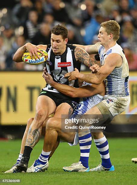 Jesse White of the Magpies is tackled by Robbie Tarrant and Jack Ziebell of the Kangaroos during the round nine AFL match between the Collingwood...