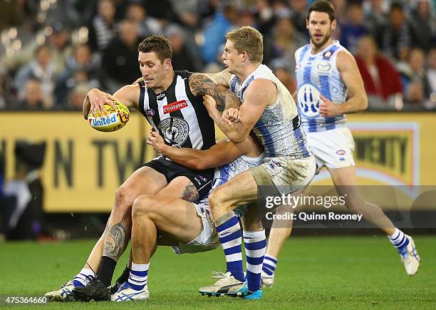 Jesse White of the Magpies is tackled by Robbie Tarrant and Jack Ziebell of the Kangaroos during the round nine AFL match between the Collingwood...