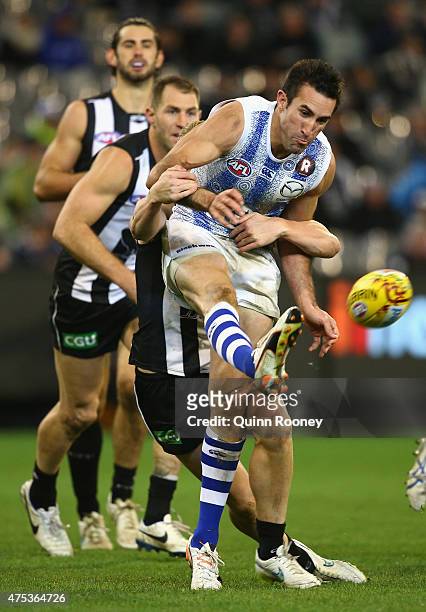 Michael Firrito of the Kangaroos kicks whilst being tackled during the round nine AFL match between the Collingwood Magpies and the North Melbourne...
