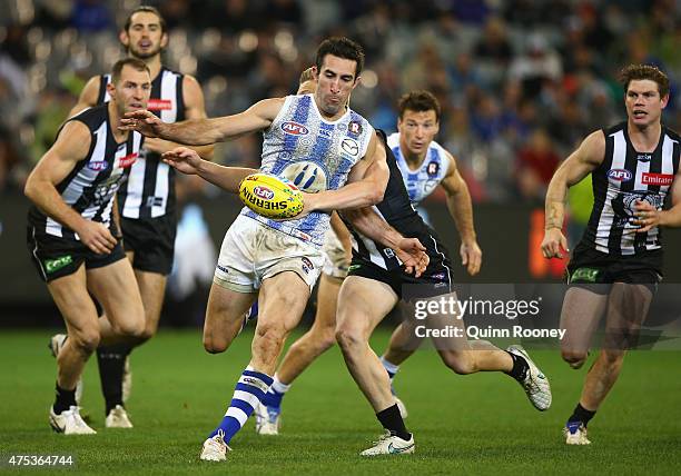 Michael Firrito of the Kangaroos kicks whilst being tackled during the round nine AFL match between the Collingwood Magpies and the North Melbourne...