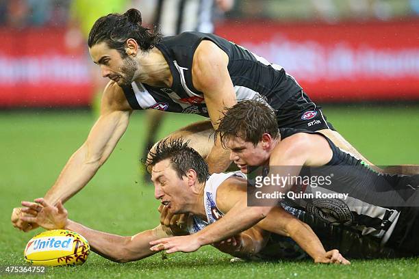 Sam Wright of the Kangaroos competes for the ball against Brodie Grundy and Tom Langdon of the Magpies during the round nine AFL match between the...