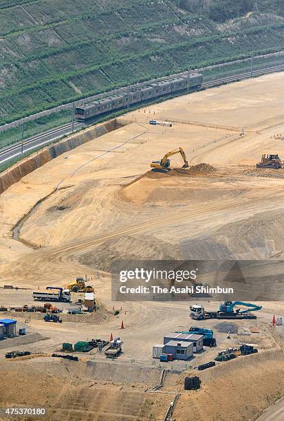 In this aerial image, a test train runs past the new residence area construction site on a hill on May 29, 2015 in Higashimatsushima, Miyagi, Japan....