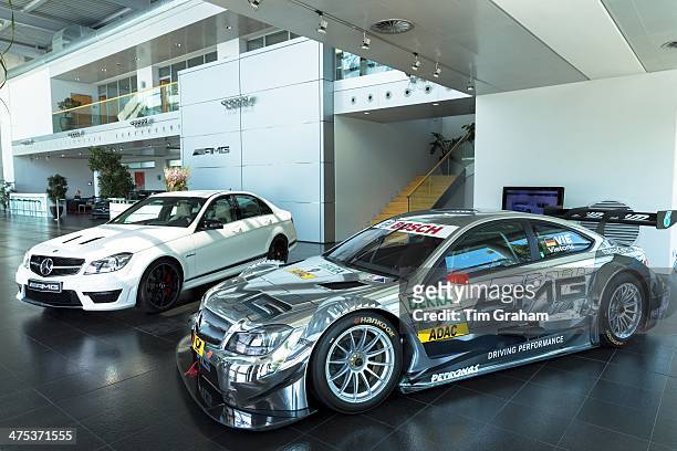 Mercedes-AMG C-Coupe 2013 race car and white CLA 45 AMG with latest 4 cylinder engine on display in showroom at engine factory in Affalterbach,...