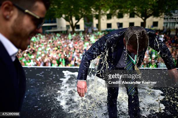 Head Coach of VfL Wolfsburg, DIeter Hecking, reacts after being shower with beer by team mates while on stage at Rathausplatz to celebrate the...