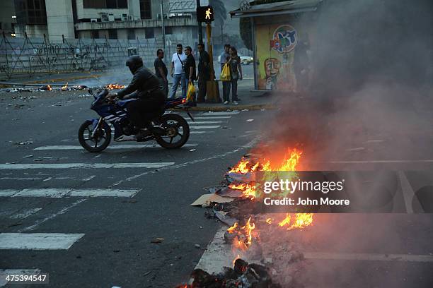 Motorcyclist rides through burning debris after an anti-government demonstration on February 27, 2014 in Caracas, Venezuela. Almost three weeks after...