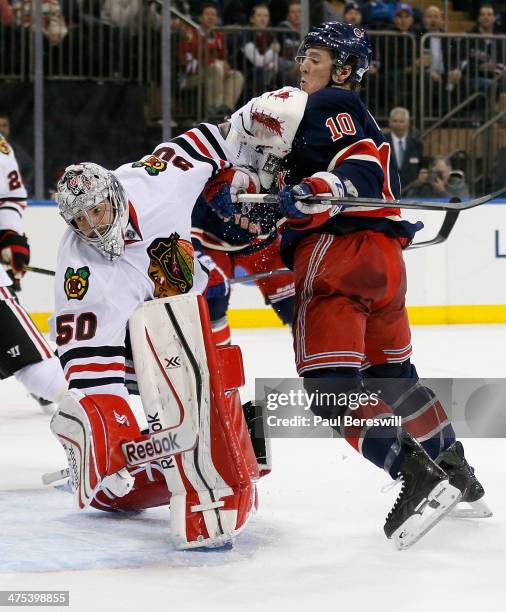 Goalie Corey Crawford of the Chicago Blackhawks stops a shot and gets an elbow up to the face of J.T. Miller of the New York Rangers in the second...