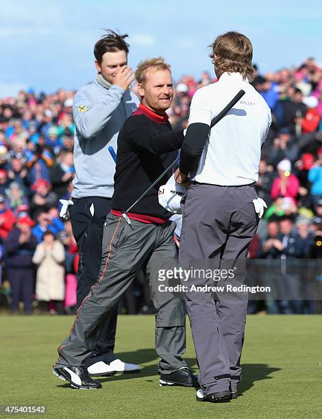 Soren Kjeldsen of Denmark is congratulated by Bernd Wiesberger of Austria and Eddie Pepperell of England after his victory in a playoff on the 18th...