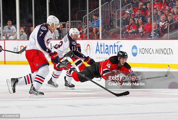 Adam Henrique of the New Jersey Devils falls to the ice after being checked by Jack Johnson of the Columbus Blue Jackets during the game at the...