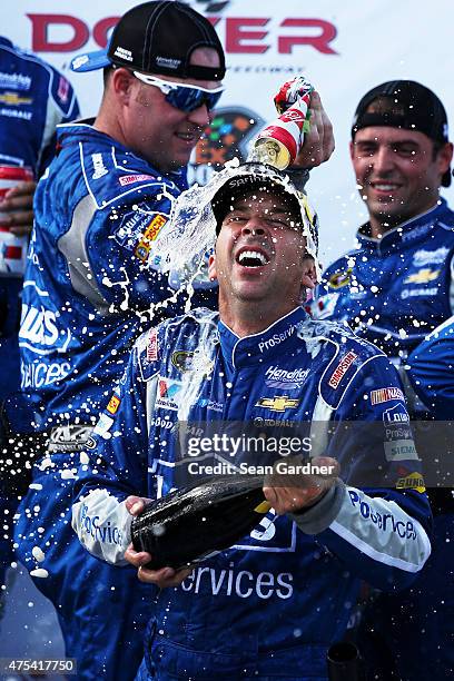 Chad Knaus, crew chief of the Lowe's Pro Services Chevrolet, front, is sprayed with champagne and beer in Victory Lane after winning the NASCAR...