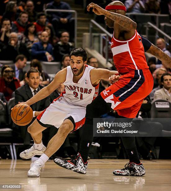 Toronto Raptors point guard Greivis Vasquez looks to pass the ball as he cut under Washington Wizards power forward Al Harrington during the game...