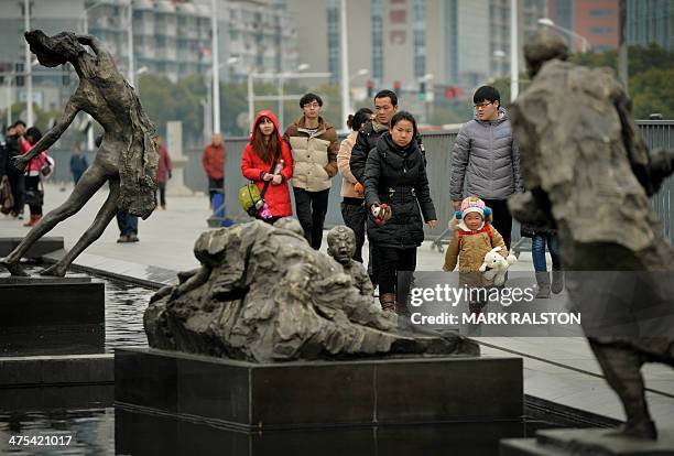 This photo taken on February 12, 2014 shows Chinese tourists beside a memorial to the victims of Japanese war crimes at the Nanjing Massacre Memorial...