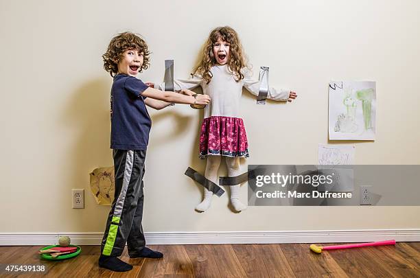 brother hung her sister on the wall - sibling argument stock pictures, royalty-free photos & images