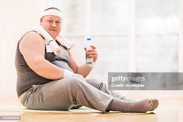fat man relaxing after exercising and looking at camera. - sitting on ground stock pictures, royalty-free photos & images