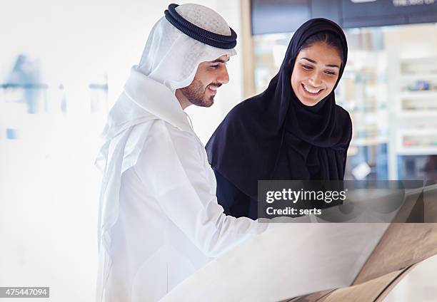 young arab couple using information display at mall - arab shopping stockfoto's en -beelden